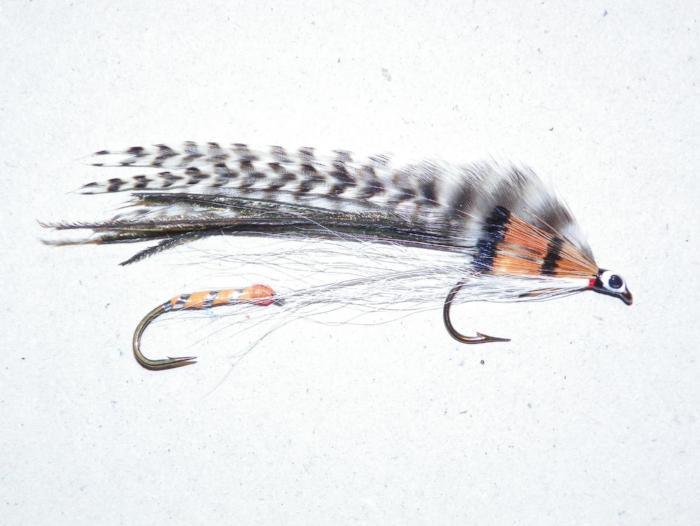 Feather fishing lure with orange-black body, striped wing, twin hooks