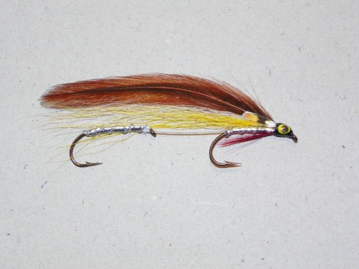 Feather fishing lure with brown wing, yellow body, red tail, green eye and two hooks