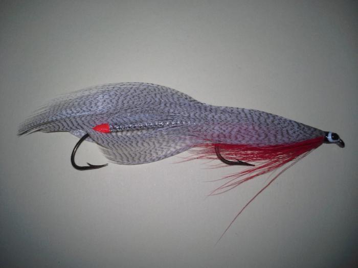 Swim bait fishing lure in gray with red accents, feather tail and treble hook