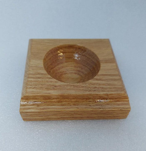 a small wooden square with a round depression used by fly tyers to hold beads, hooks, and other small items