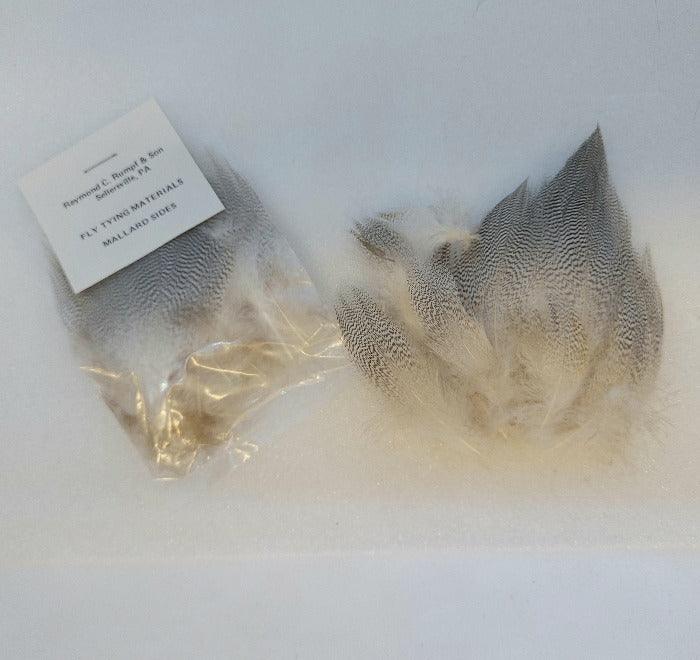 a package of natural color mallard flank feathers and a package opened to show the different sizes of feathers