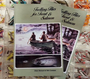 2 copies of the book trolling flies for trout and salmon by Dick Stewart and Bob Leeman sitting on top of  a display of streamer flies
