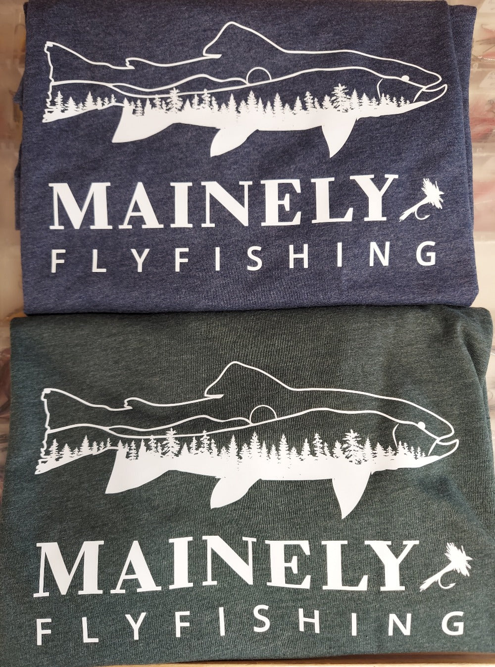 two colors of tee shirts with a fish/landscape design