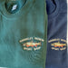 a navy and a forest green crew neck sweatshirt with an embroidered brook trout and shop name