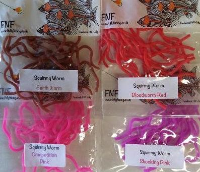 Assorted bagged plastic worm toys in tan, red, purple, and pink colors.