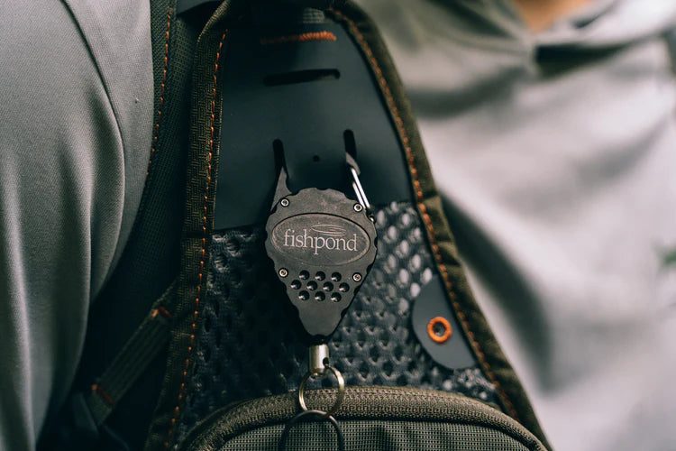 Fishpond Arrowhead Retractor on dark bag, black retracting clip with carabiner