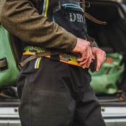 Wading belt worn with dark waders, multicolor fish-pattern strap and black buckle