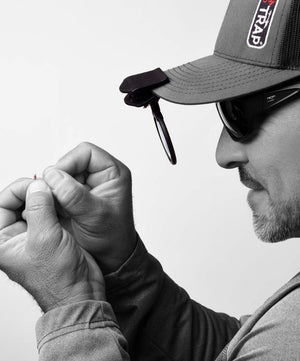 a person tying on a fly using his magnifly device attached to his hat