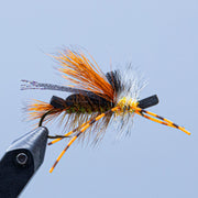 Tied foam fly on hook with orange, white, and black foam and feather fibers