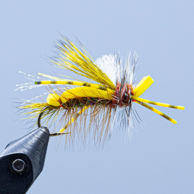 Tied foam fly on hook with yellow foam wings and white feather fibers