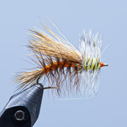 Fishing fly lure with orange-brown body and pale blue-white hackle feathers on hook