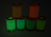 Glow tinsel thread spools glowing green with orange and brown accents