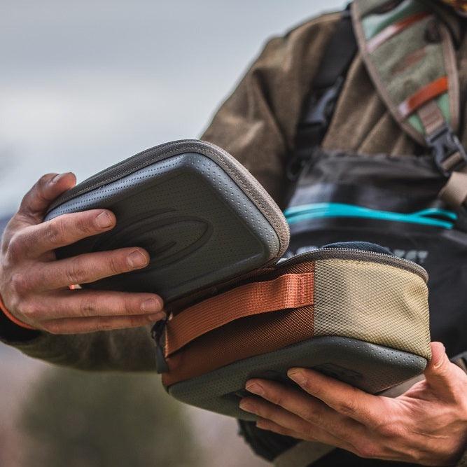 Someone holding a Fishpond reel case with a cheeky reel and two spare spools
