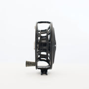 Fishing reel, matte black side view with arched cutouts and dark knob grip
