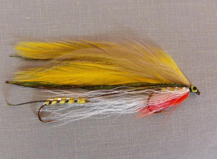 Fishing lure fly with yellow feather wing, red tail, and white thread body