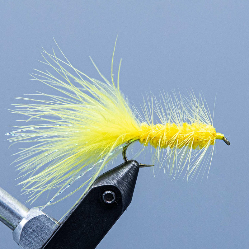 Fly streamer with bright yellow marabou tail on a hook